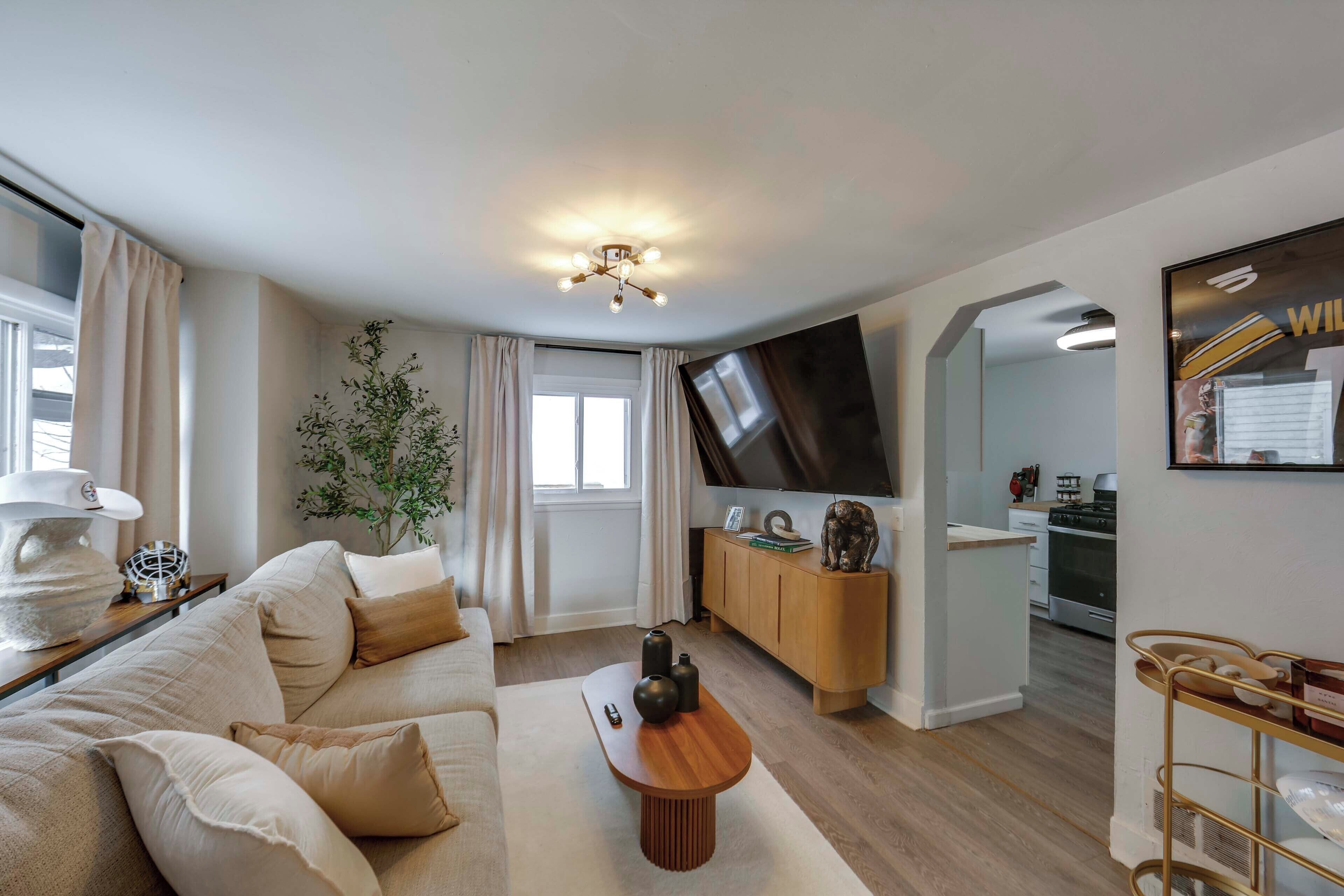 A modern living room with a sofa, coffee table, and a TV mounted on the wall.
