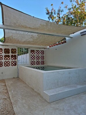 A covered outdoor area with a pool, concrete steps, and decorative lattice panels. - Merida Centro House with Private Pool and Air Conditioning (Mérida)
