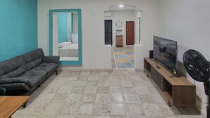 A living room with a sofa, TV, and fan. - Merida Centro House with Private Pool and Air Conditioning (Mérida)