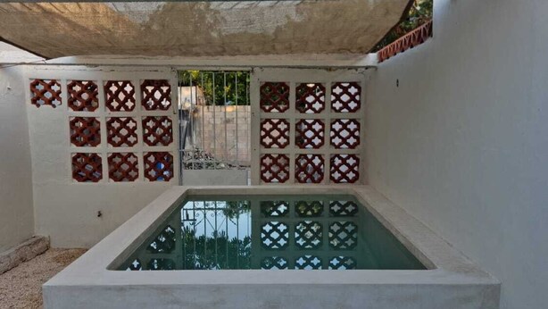 A swimming pool with a geometric tile design, surrounded by a concrete deck and a shaded area. - Merida Centro House with Private Pool and Air Conditioning (Mérida)
