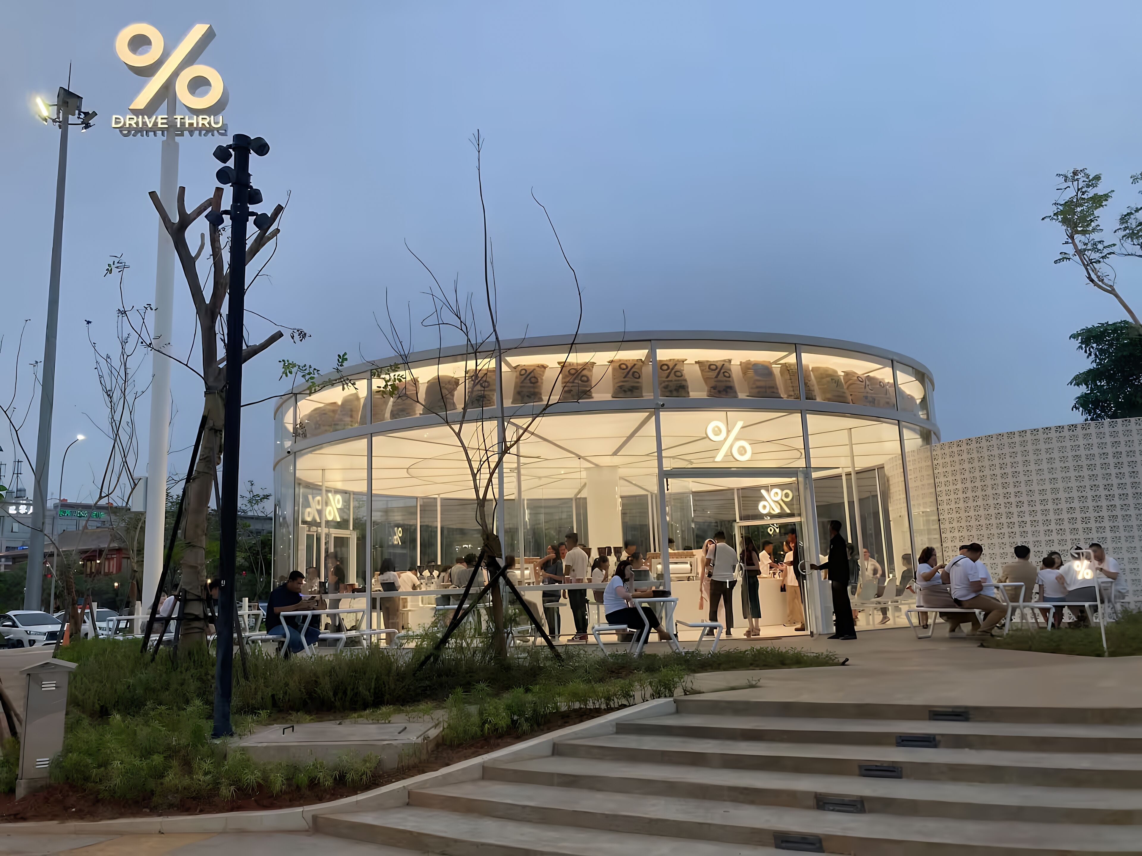 Un bâtiment moderne doté d’une façade en verre, d’une terrasse et d’une conception circulaire.