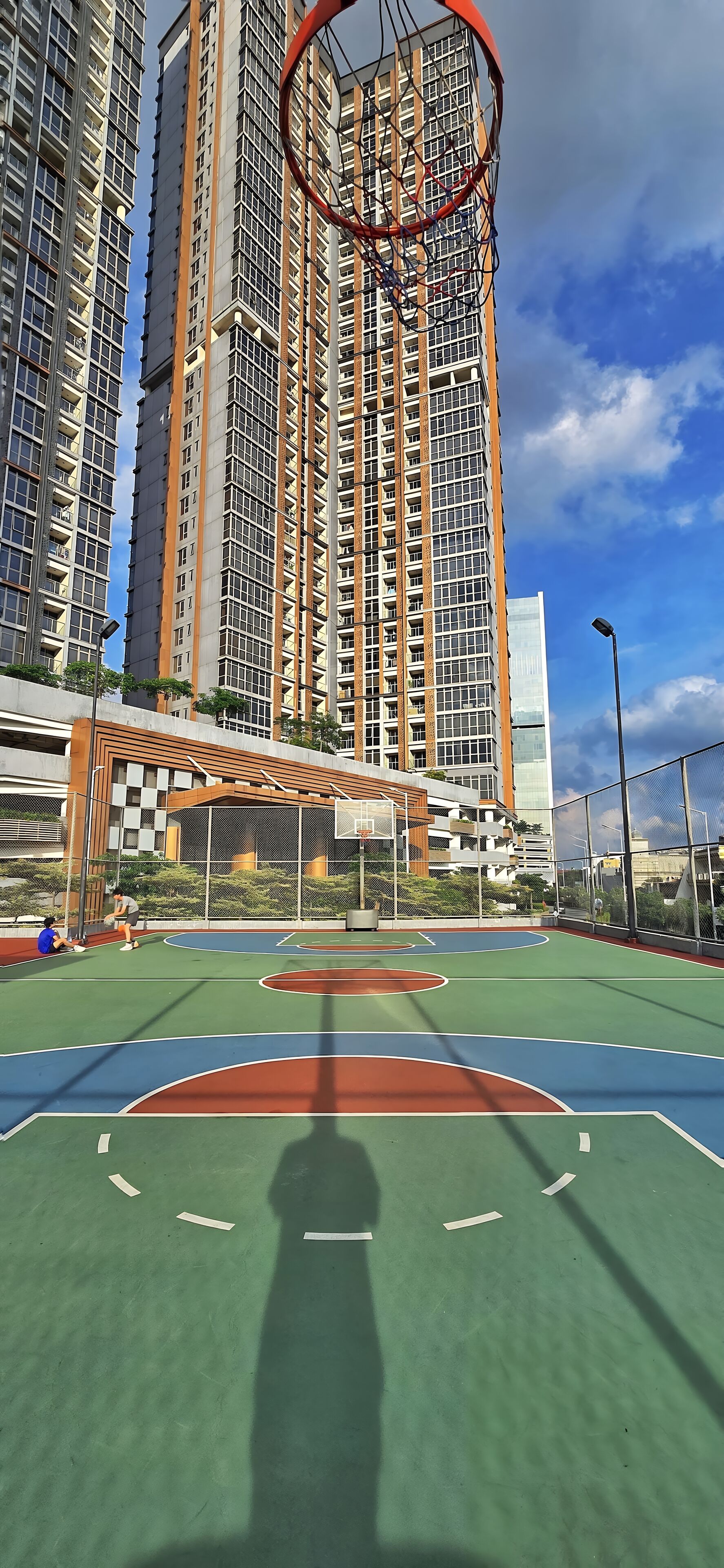 A basketball court with a hoop, surrounded by tall residential buildings.