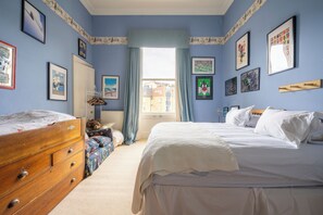 A bedroom with a large bed, a dresser, a wardrobe, and a window with curtains.