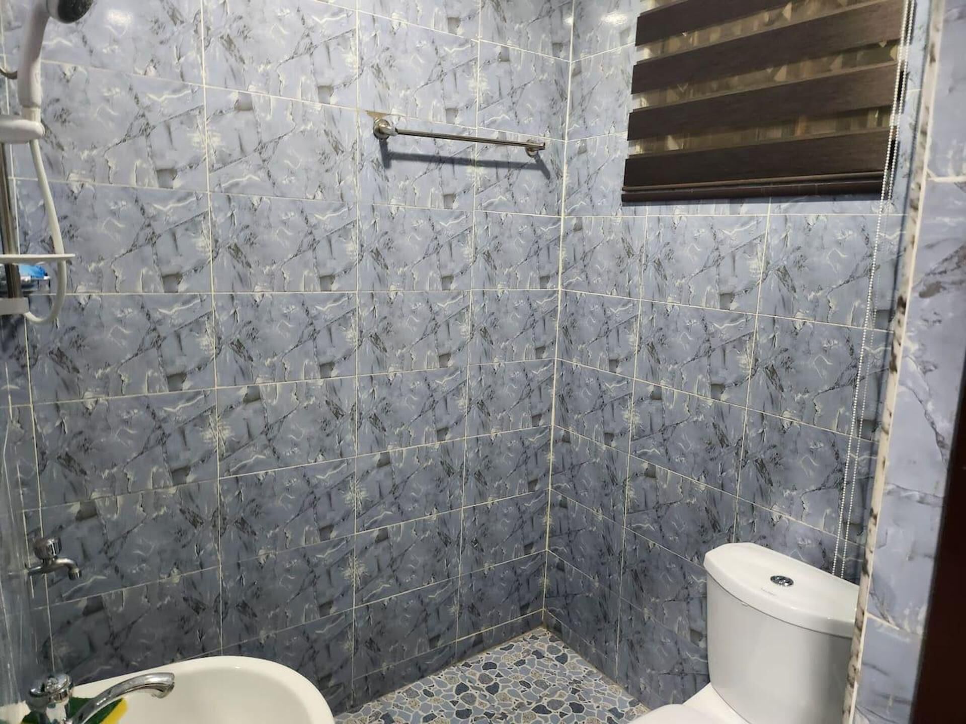 Un baño con azulejos de mármol, una bañera, un inodoro y una zona de ducha.