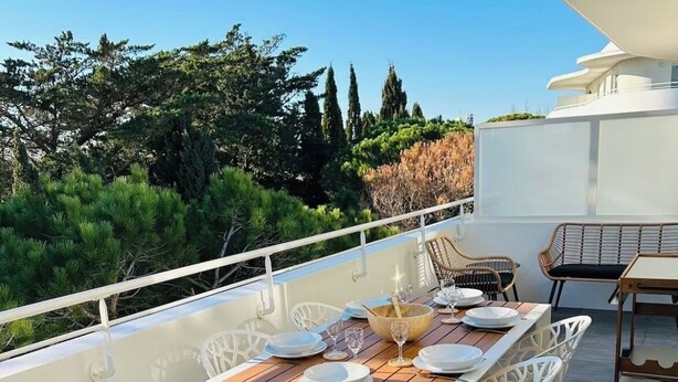 Une terrasse sur le toit avec une table à manger pour quatre personnes, entourée de chaises blanches.
