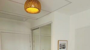 Un couloir avec une porte coulissante, un tableau encadré au mur et un luminaire au plafond à texture particulière.