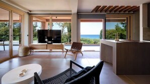 Un salon moderne avec un téléviseur, des sièges et une vue sur la mer.