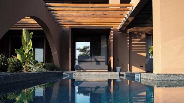 Un espace piscine moderne offrant une vue dégagée sur la piscine, agrémenté d’une pergola en bois et d’une végétation luxuriante.