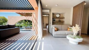 Un salon moderne avec un canapé, une table basse agrémentée de plantes et une vue sur l’extérieur.