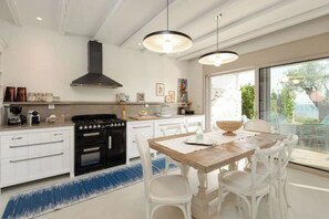 A modern kitchen with white cabinetry, a black stove, and pendant lighting. - Villa Pathos: Beachfront Bliss with Pool & Panoramic Views/3 bdrs (Nikiti)