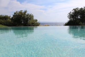 A clear swimming pool with a view of the sea and trees. - Villa Pathos: Beachfront Bliss with Pool & Panoramic Views/3 bdrs (Nikiti)