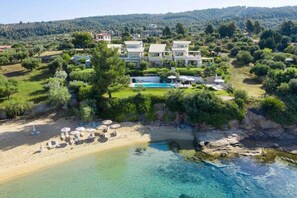 A coastal property with a swimming pool, beach, and lush greenery. - Villa Pathos: Beachfront Bliss with Pool & Panoramic Views/3 bdrs (Nikiti)