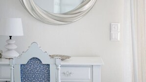 Un tocador blanco con cabecera azul estampada, un espejo y una lámpara.