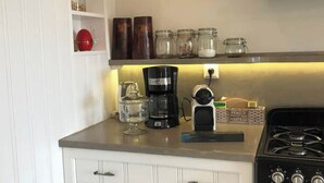 Una cocina con estufa, cafetera y frascos en la encimera.