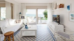 Habitación de hotel moderna con cama, una mesita de café, televisor y vistas al exterior.