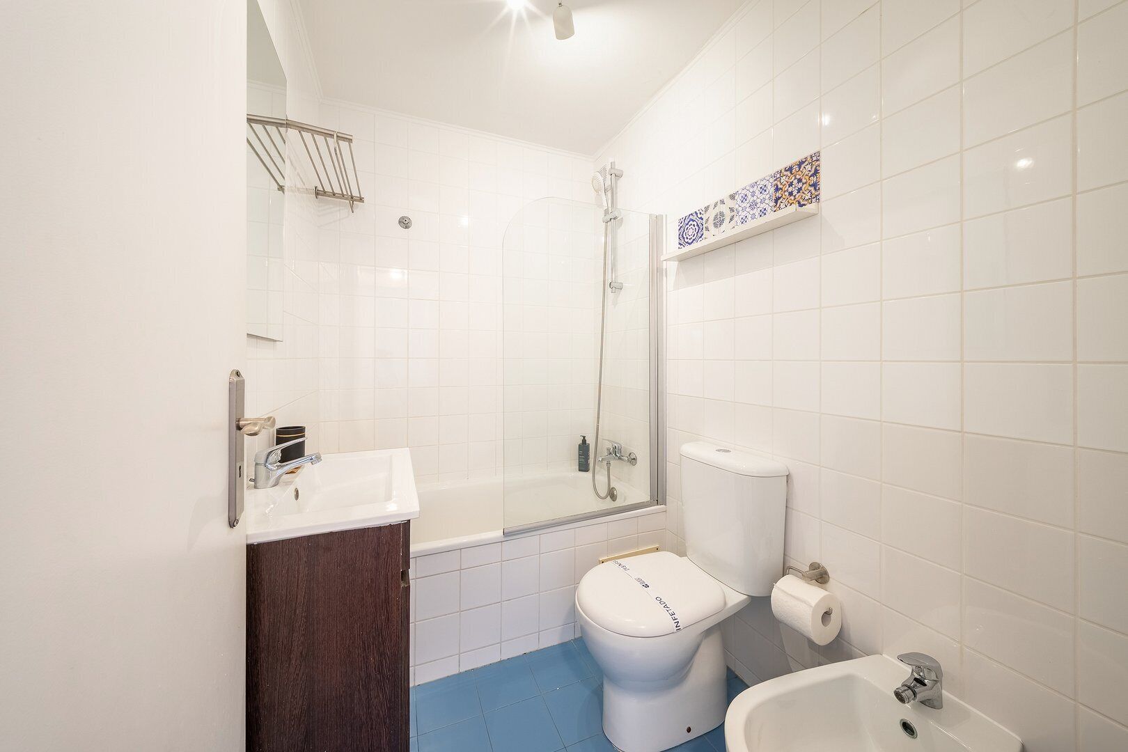 Un baño moderno con ducha de vidrio, inodoro blanco, lavamanos y bidé.