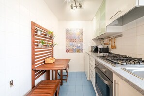 A compact kitchen with a wooden bench, a tiled backsplash, and a gas stove. - GuestReady-Charming Lisbon Retreat (Lisbon)
