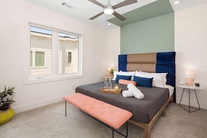 A bedroom with a bed, bench, bedside table, lamp, and a window. - Retro East Nashville townhouse, neon sign, king suites, sleeps 10 (Nashville)