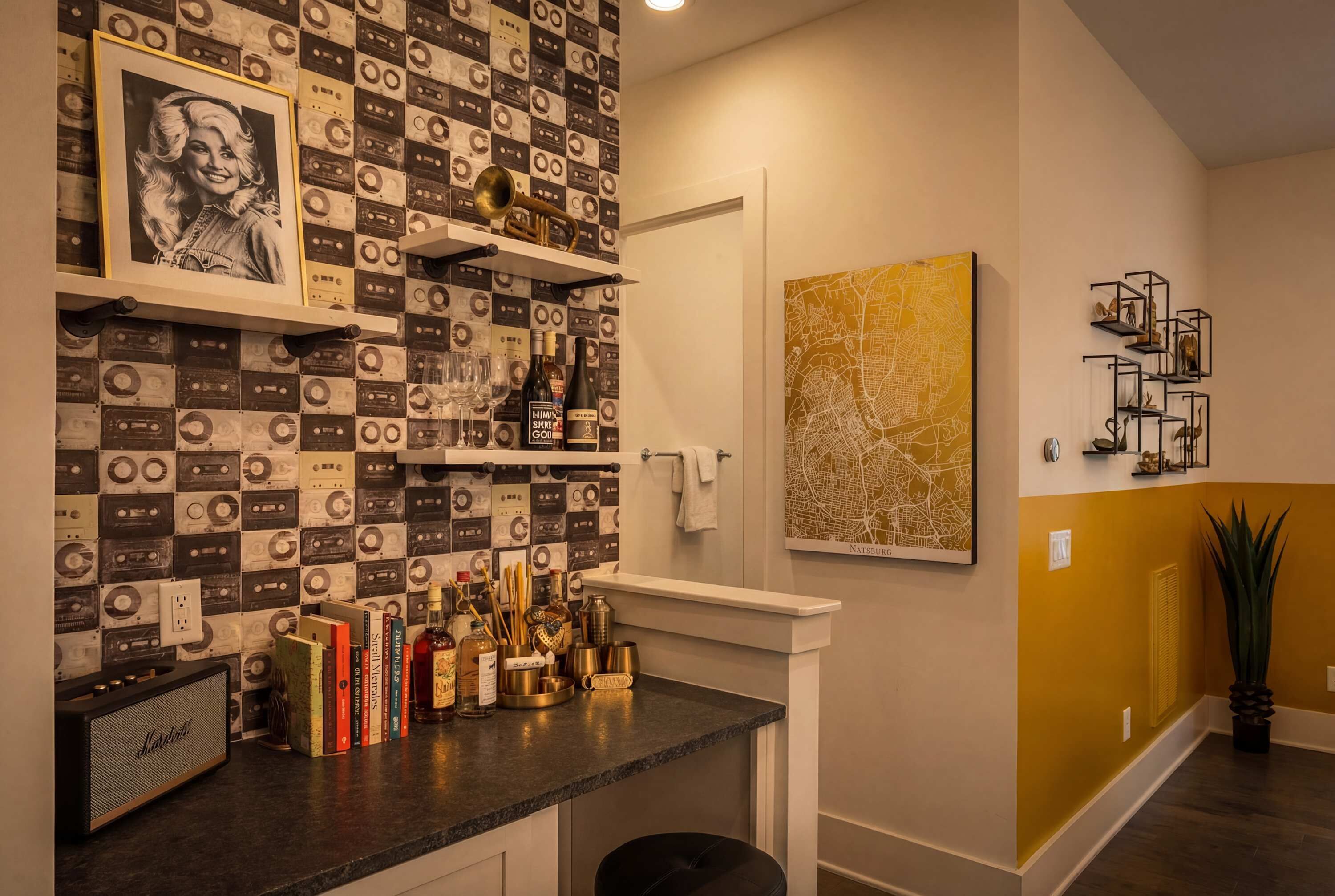 A bar area with a wall of cassette tapes, a framed picture, and various bottles and glasses.