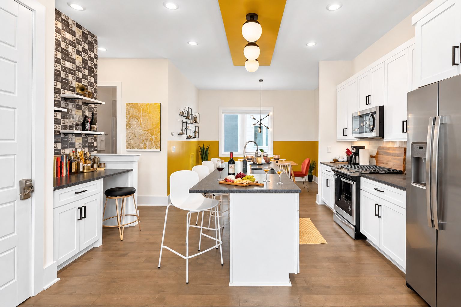 Een moderne keuken met witte kasten, een centraal kookeiland met barstoelen, een ingebouwde oven en een roestvrijstalen koelkast.