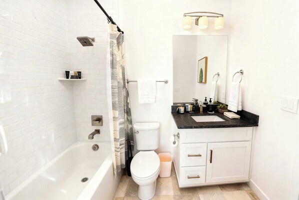 Une salle de bain moderne équipée d’une baignoire, de toilettes et d’un meuble-lavabo.
