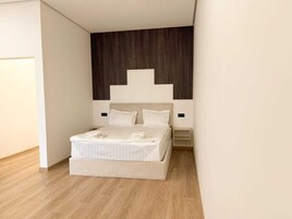Un dormitorio moderno con cama, suelo de madera y una pared revestida de madera oscura.