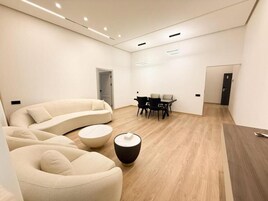 Una sala de estar moderna con un sofá curvo, una mesa redonda y un comedor con mesa y sillas.