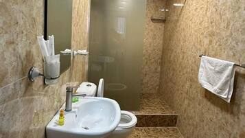 A bathroom with a sink, toilet, and shower.