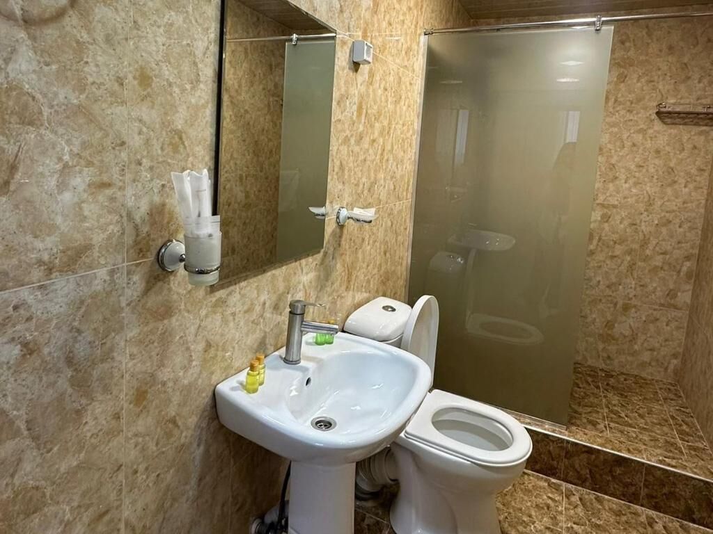 Un baño con lavamanos, inodoro y ducha con mampara de vidrio.
