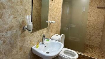 Un baño con lavamanos, inodoro y ducha con mampara de vidrio.
