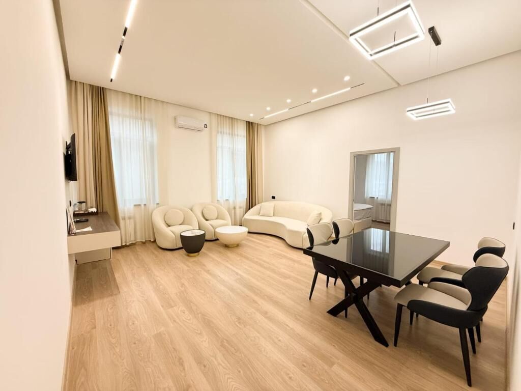 A modern living room with a sofa, a coffee table, and a dining table with chairs.