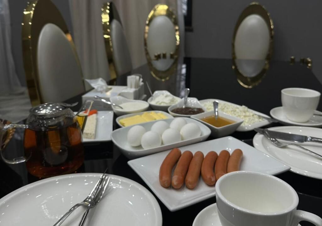 A breakfast setting with plates of eggs, sausages, and various condiments.