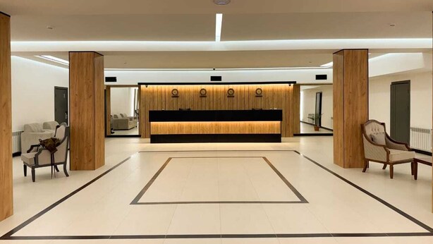 A spacious lobby with a reception desk, wooden pillars, and seating areas.