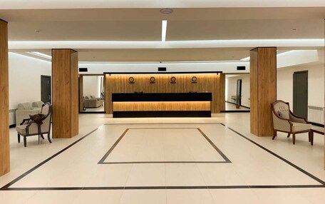 A spacious lobby with a reception desk, wooden pillars, and seating areas.