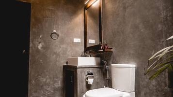 Une salle de bain moderne avec des toilettes blanches, un miroir rectangulaire et un petit lavabo.