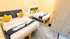 A hotel room with two beds, each with a headboard, a bedside table, and a mirror. - GANGA KASHTI (Varanasi)