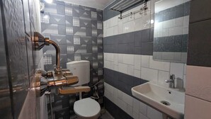 A bathroom with a toilet, sink, and shower with a modern design. - GANGA KASHTI (Varanasi)