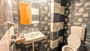 A bathroom with a sink, mirror, toilet, and shower. - GANGA KASHTI (Varanasi)
