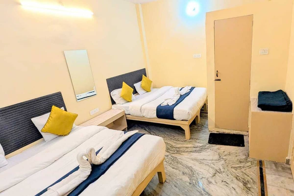 A hotel room with two beds, each with a headboard, a wardrobe, and a mirror on the wall.