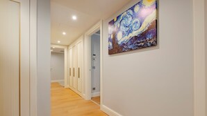 Un couloir doté d’un plancher en bois, de murs blancs et d’un tableau représentant un ciel nocturne tourbillonnant.