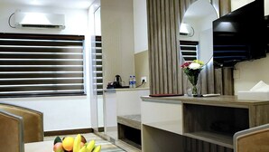 A modern hotel room with a dining area, a TV, and a large window with blinds. - Sri Suryas Hotels (Colombo)