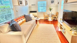 A modern living room with a sofa, coffee table, TV, and a small dining area. - Coastal Beach Bungalow walking distance to beach, coffee, and restaurants (Redondo Beach)