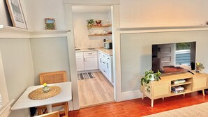 A modern living room with a fireplace, a dining area with a table and chairs, and a kitchen visible through an open doorway. - Coastal Beach Bungalow walking distance to beach, coffee, and restaurants (Redondo Beach)
