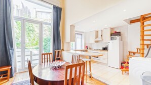 A modern kitchen with a dining area, large windows, and a view of greenery. - Prime Location Apartment Châtelain Saint-gilles Quiet & Central (Brussels)