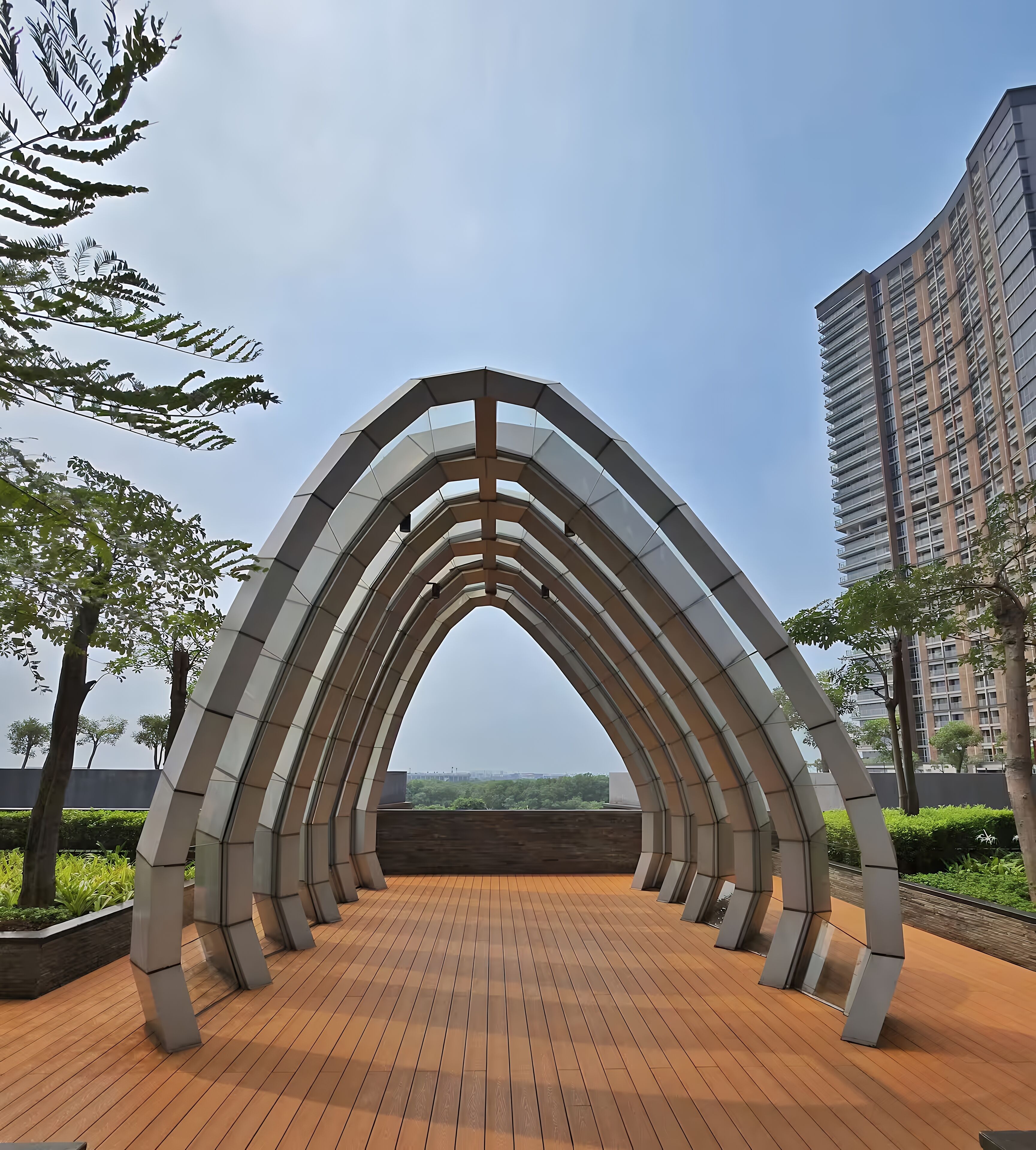 A modern architectural structure with a series of arches and a wooden deck.