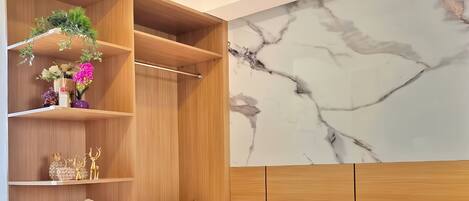 Une chambre d’hôtel moderne avec un grand lit, une armoire en bois et un mur en marbre.