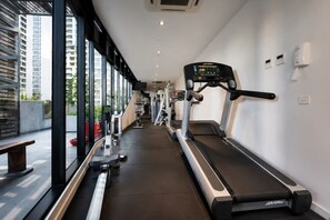 Ein Fitnessraum mit Laufbändern, Trainingsgeräten und einer Bank.