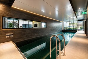 Ein Hallenbad mit Tiefenhinweis, Metallgeländern und modernem Design mit Glaswänden.