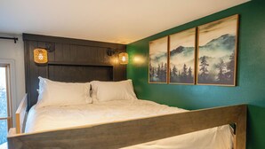 A bedroom with a wooden bed, two wall-mounted lamps, and a large landscape painting. - Family Retreat- Sauna, Arcade, Gym & Message Chair (Helena)