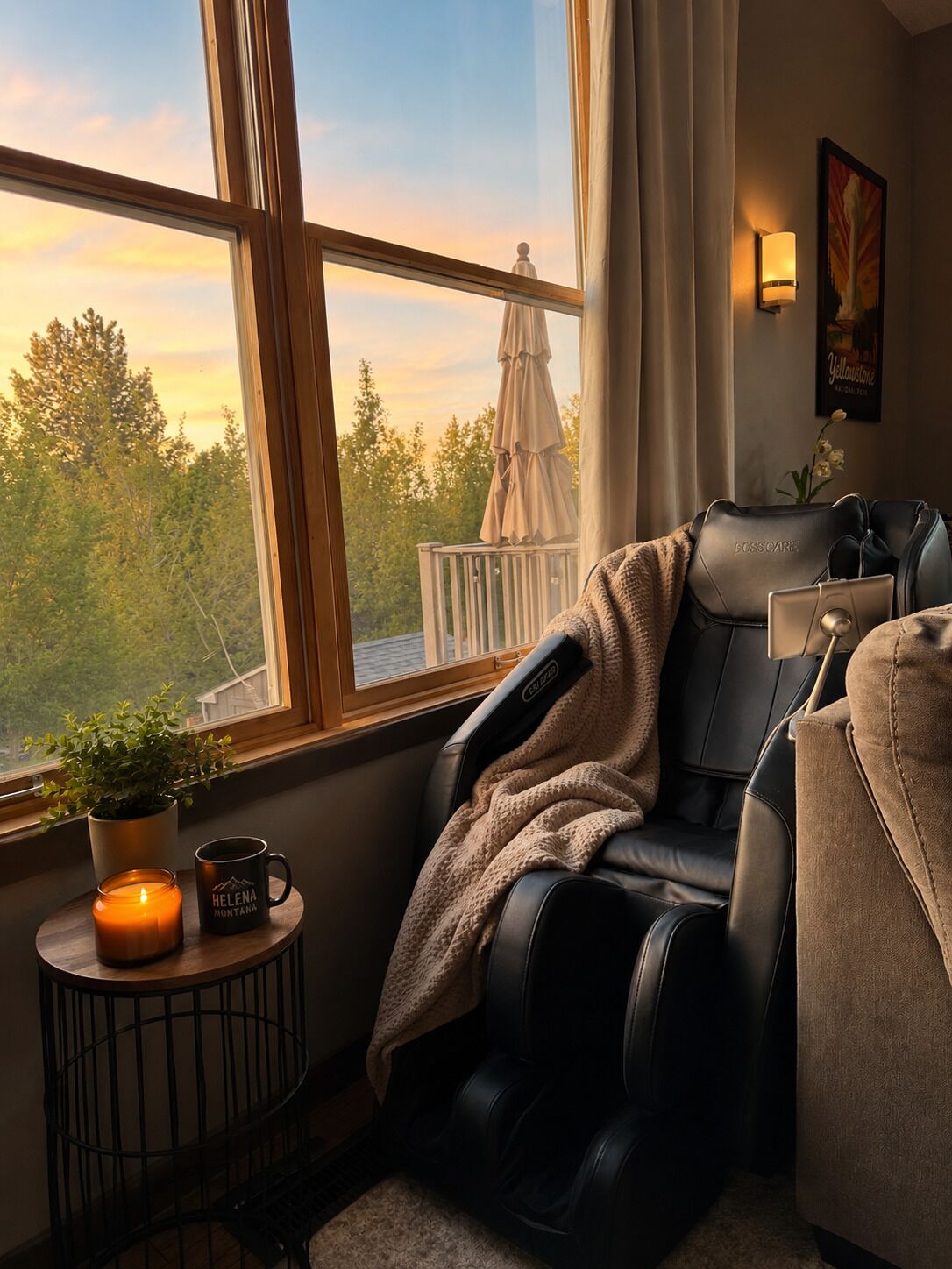Un fauteuil de massage de la marque BOSSCARE, placé dans une pièce dotée d’une grande fenêtre, d’une plante en pot, d’une bougie et d’une tasse.